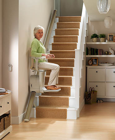 Elderly Lady on Stair Lift After Finding Out About Stairlift Costs in Rochester, Buffalo, Erie